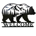 Black metal wall art featuring a bear silhouette filled with a mountain, pine tree forest, and river scene, with the word WELCOME cut across the bottom, shown on a plain white background.